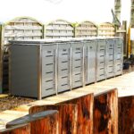 Mehrere Mülltonnenboxen in moderner Gartenumgebung mit Beschriftung Papier, Glas, Plastik und Rest vor Holzsichtschutz